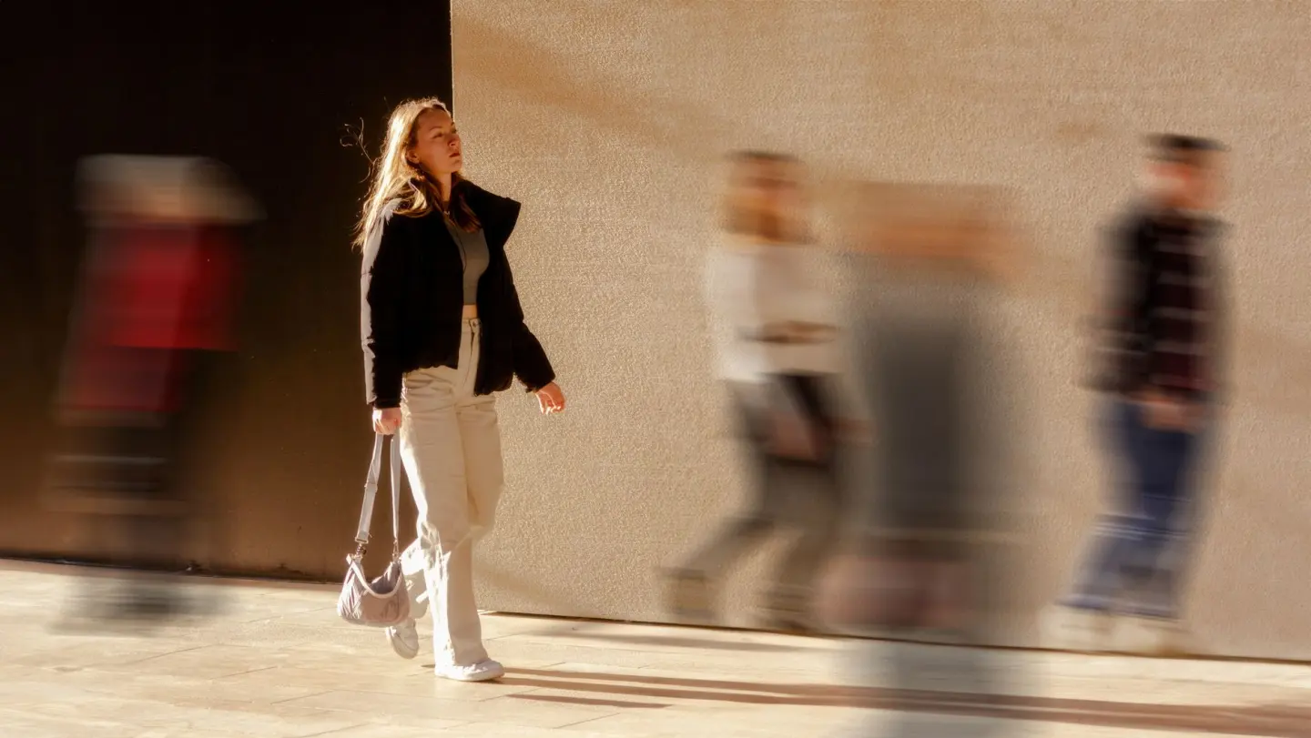 A woman walking with motion blur effect, highlighting city life dynamics.