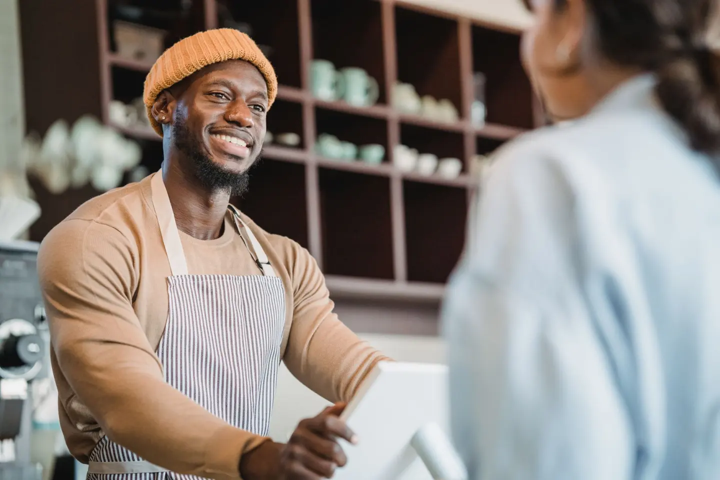 A smiling barista taking an order from a customer at a café counter, creating a warm atmosphere.